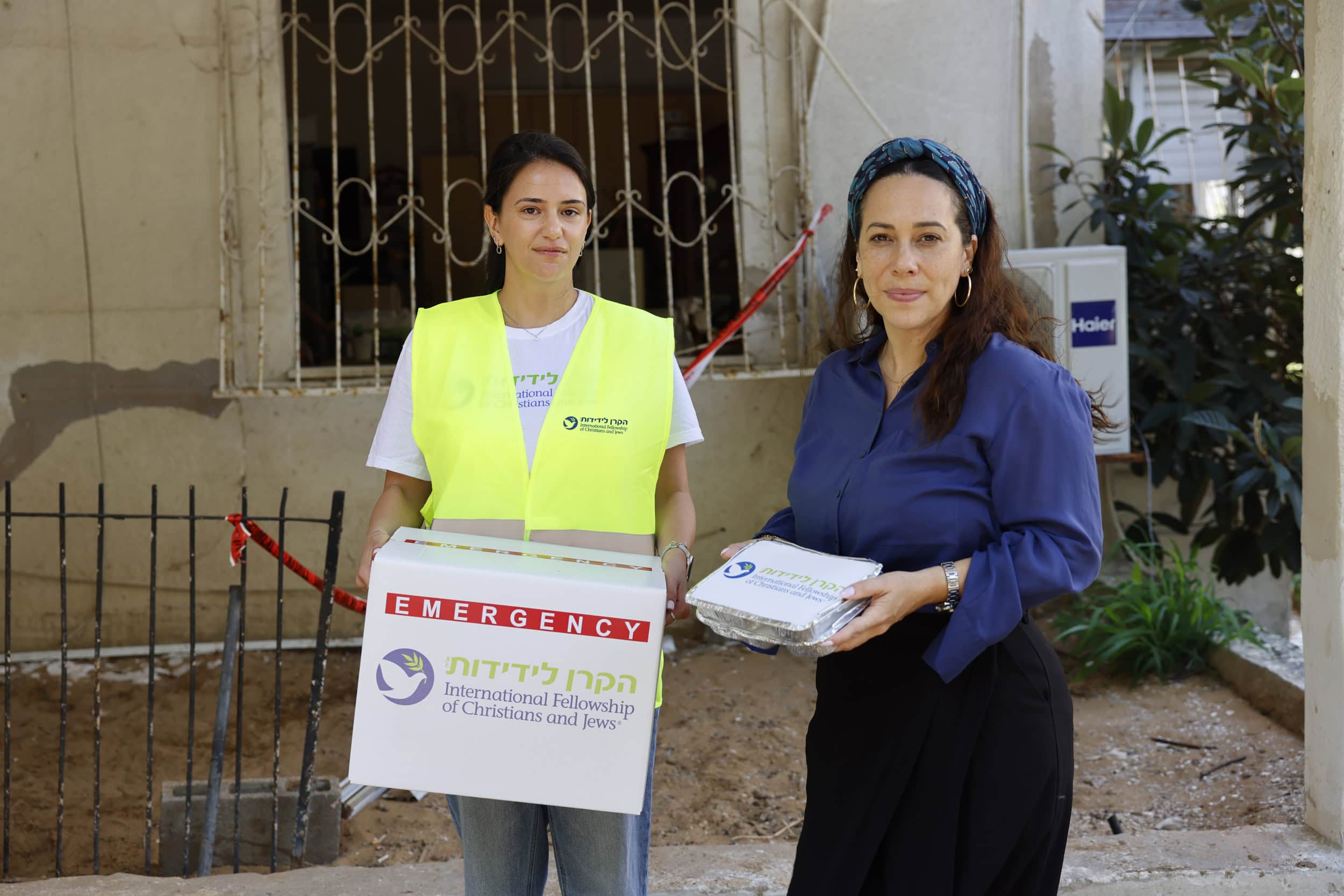 נשיאת הקרן לידידות- יעל אקשטיין, ומתנדבת מהקרן מחזיקות חבילות מזון וחירום של הקרן לידידות במסגרת חלוקת סיוע.